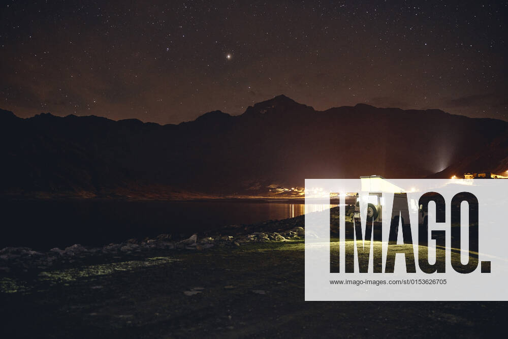 Illuminated off-road vehicle by reservoir at night, Splugen Pass, Sondrio, Switzerland property released, SSCF00853