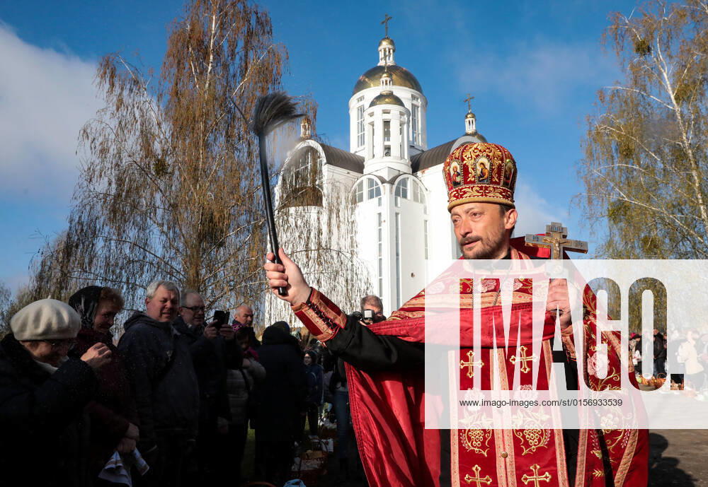 BUCHA, UKRAINE - APRIL 24, 2022 - A priest blesses people and their baskets with holy water outside the Church of Saint Andrew the First-Called Apostle during the Orthodox Easter celebration in Bucha that is recovering from the war crimes committed by Russian troops after its liberation from Russian invaders, Kyiv Region, northern Ukraine. Easter service in Bucha