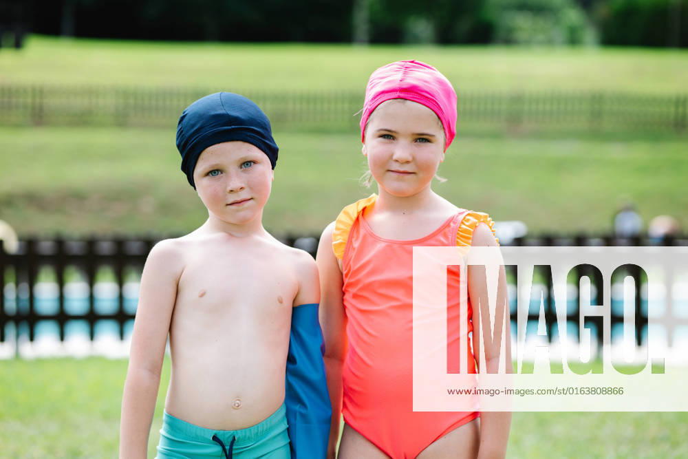 Adorable little sister and brother in swimwear and hats standing on green grassy lawn at poolside and looking at camera during summer vacation, Model released HodeiUnzueta_ChildrenAndGrandfatherInPool_24.jpg
