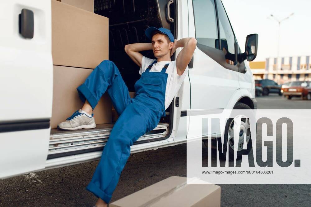 IMAGO Creative: Business, Inflation und Lieferketten Deliveryman relaxing in the car during a break, Deliveryman in uniform relaxing in the car during a break, auto with parcels and carton boxes, delivery service. Man poses at cardboard packages in vehicle, male deliver, courier or shipping job model released, Symbolfoto , 05.02.2020 10:34:29,