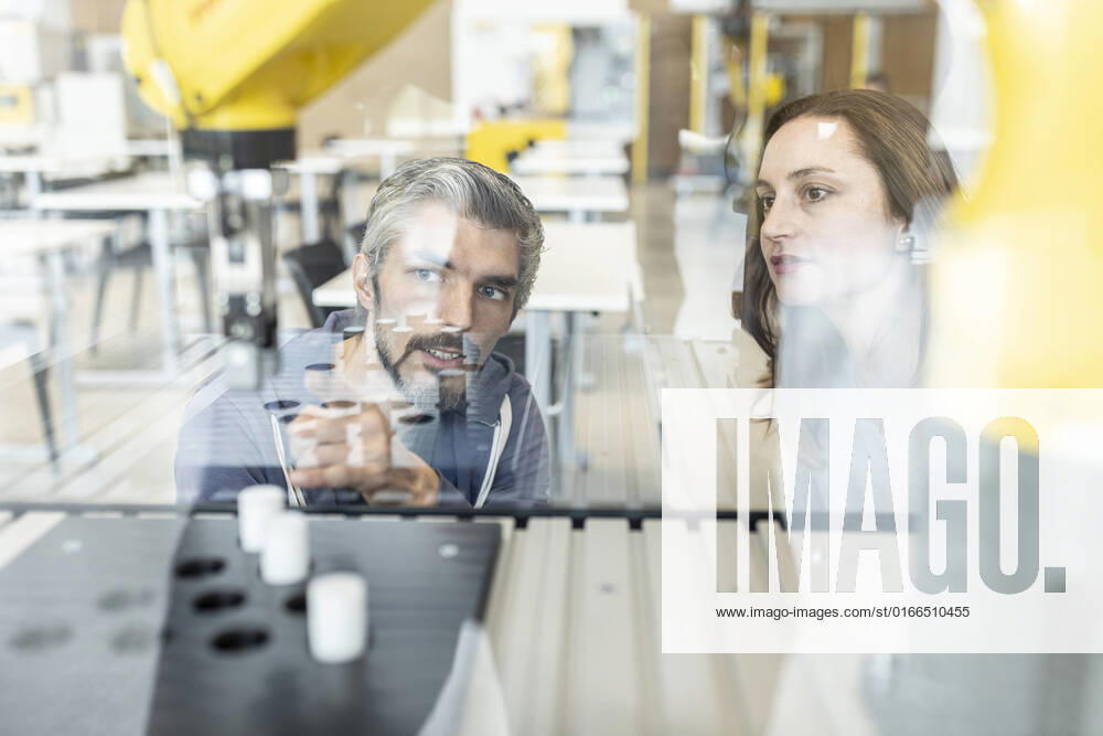 IMAGO Creative: Business, Inflation und Lieferketten Engineers testing industrial robot in glass cabin model released, Symbolfoto property released, WESTF24846