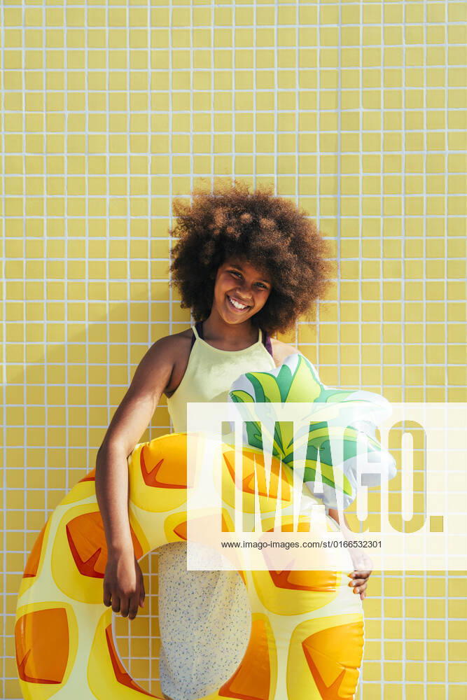 IMAGO Creative: Ende des Sommers Smiling girl with inflatable ring standing in front of yellow wall model released, Symbolfoto, OIPF02198