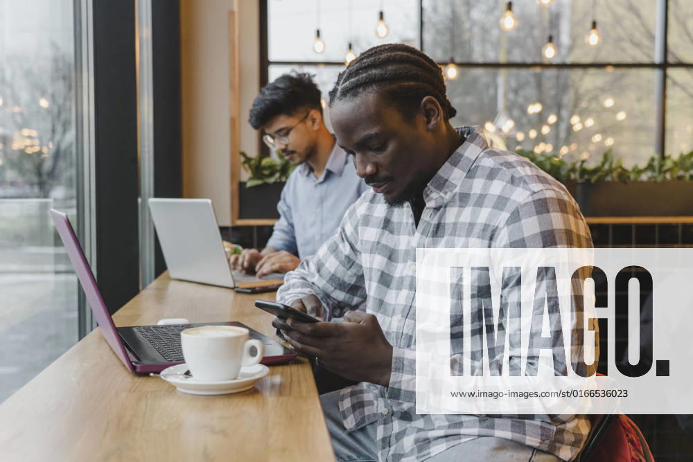 IMAGO Creative: Business, Innovative Technologie-Lösungen Young freelancer using mobile phone at cafe model released, Symbolfoto property released, OSF00327