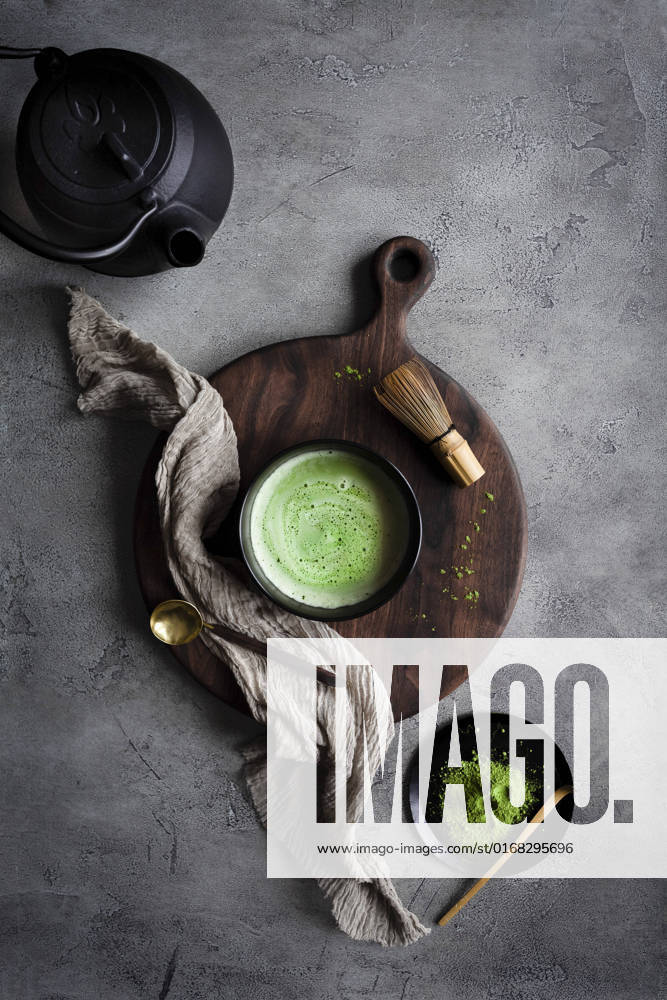 Matcha tea with a kettle and whisk on a dark surface Matcha tea with a kettle and whisk on a dark surface