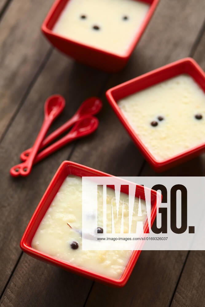Three red bowls of the Ecuadorian dessert called morocho (coarsely ground white corn) cooked with milk, sugar and spices (cinnamon and allspice), similarly to rice pudding (Selective Focus, Focus into the middle of the lower bowl) , 14343482.jpg, morocho, cooked, sweet, dessert, pudding, food, milk, spice, condiment, cinnamon, allspice, newspice, Jamaica pepper , prepared, Ecuador, Ecuadorian, traditional, corn, maize, ground, coarse, kernel, porridge, bowl, red, vertical, white,