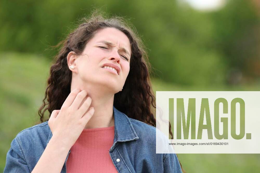 Overwhelmed woman scratching itchy neck in a park, Overwhelmed woman scratching itchy neck standing in a park, Overwhelmed woman scratching itchy neck standing in a park model released, Symbolfoto , 16.05.2022,