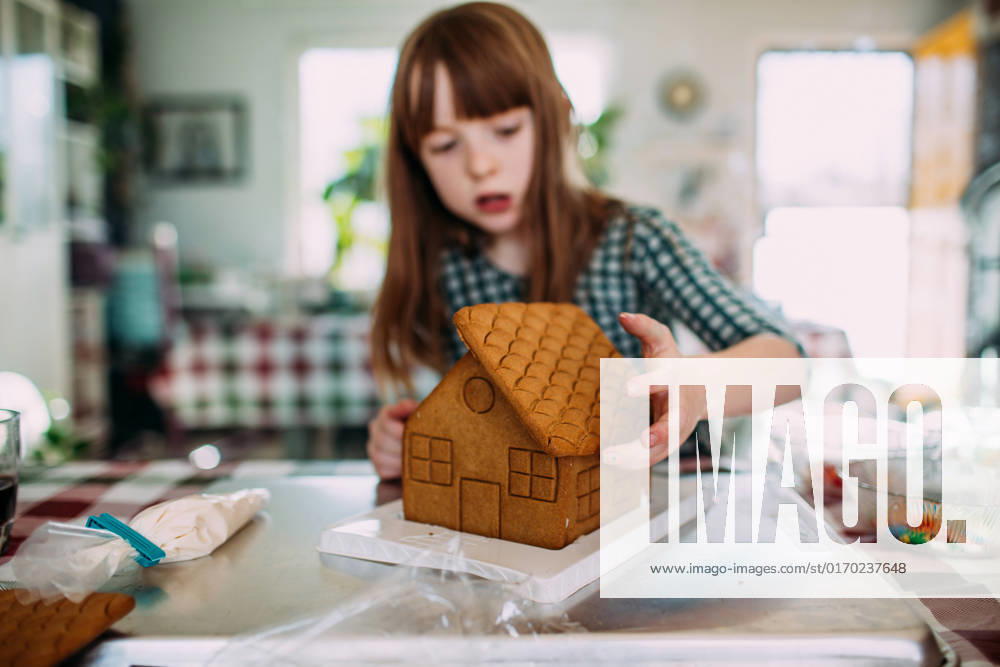 Young girl building a gingerbread house at the dining room table Denver, CO, United States CR_JEMI210628-607452-01 ,model released, Symbolfoto