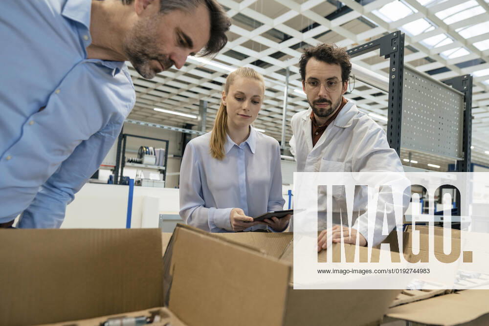 IMAGO Creative: Business, Inflation und Lieferketten Engineer standing by businessman and businesswoman examining equipment in box at factory model released, Symbolfoto property released, JOSEF13282