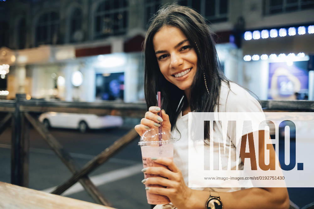 IMAGO Creative, Jahreszeit Sommer, Sommer in der Stadt Happy beautiful woman with smoothie at sidewalk cafe model released, Symbolfoto, OYF00801
