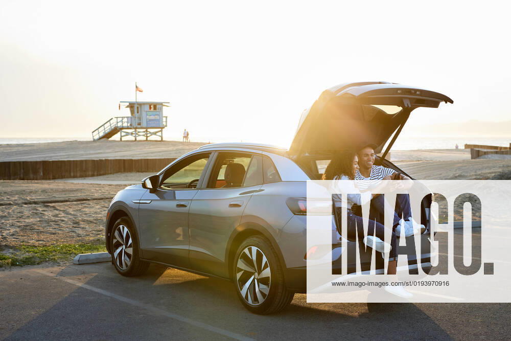 IMAGO Creative: Business, Innovative Technologie-Lösungen Heterosexual couple using smart phone sitting in car trunk Los Angeles, California, United States CR_JAJEES221114-1070948-01 ,model released, Symbolfoto