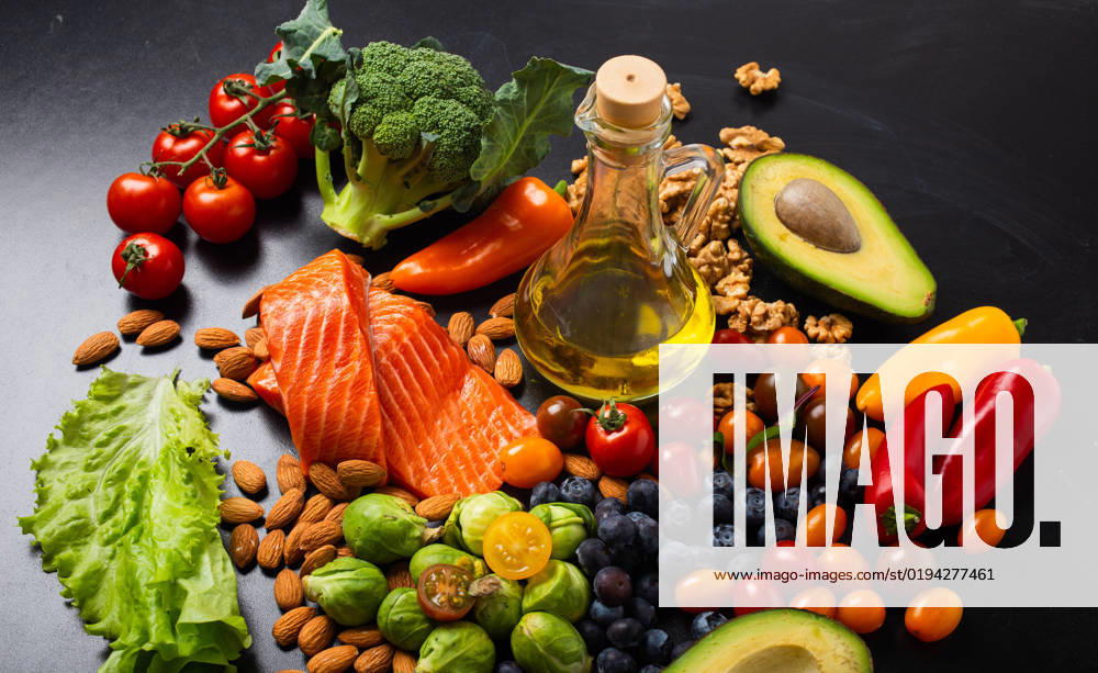 Healthy diet and nutrition food rich in vitamins and omega-3 concept Healthy diet and nutrition food rich in vitamins and omega-3 concept, assorted fresh vegetables, green salad, fruit, fish salmon, nuts, blueberries, bottle of olive oil on black chalk board background.