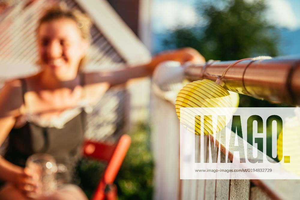 Summer feeling on the balcony: Close up of lampions, smiling girl in the blurry background Close up of summer lampions on a balcony, girl in the blurry background. Leisure time in the summer holidays
