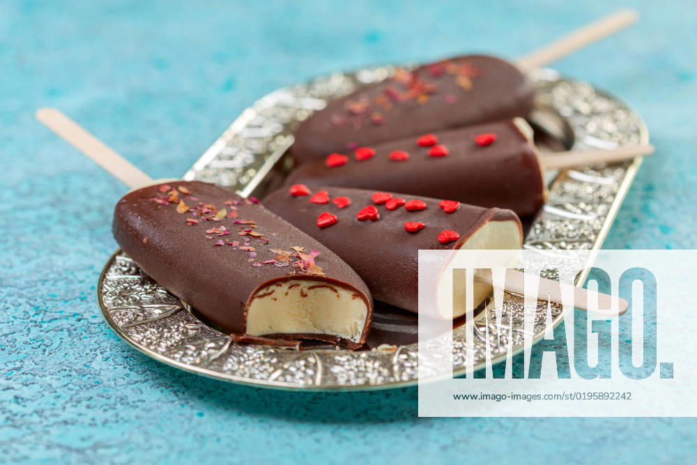 Homemade ice cream on a stick in dark chocolate icing. Homemade vanilla ice cream on a stick in dark chocolate glaze on a metal tray close up, selective focus.