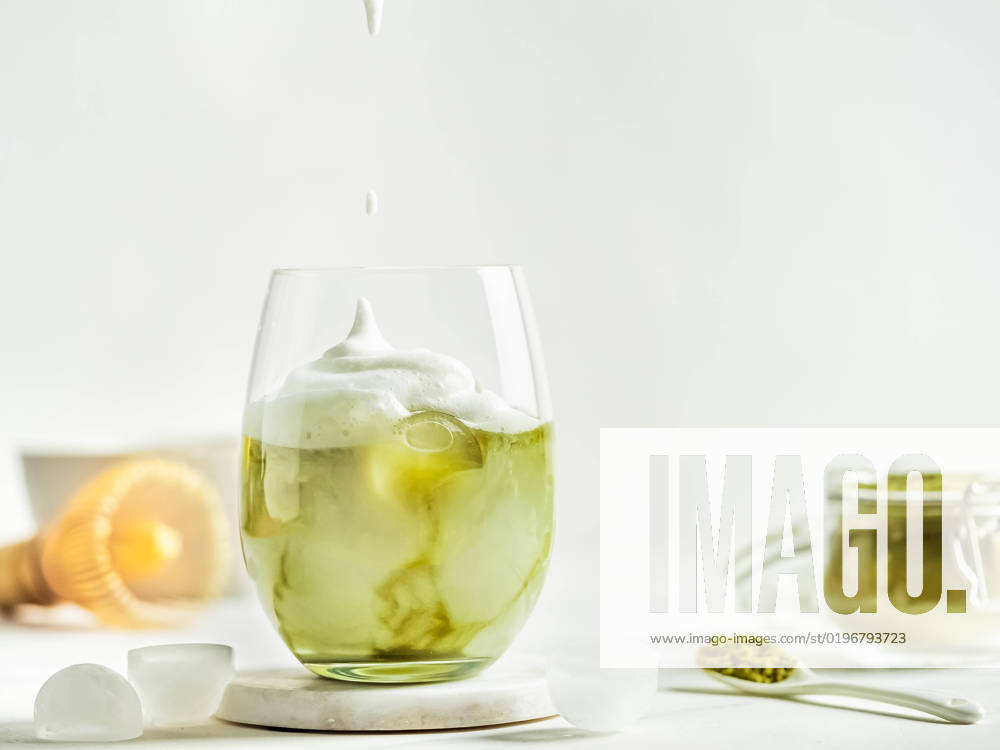 Iced Matcha Latte Tea with whipped cream Iced Matcha Latte Tea with whipped cream in tumbler glass and ingredients on white marble background. Copy space for txt or design
