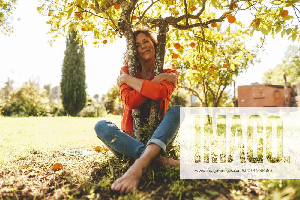 Mature woman with eyes closed hugging orange fruit tree model released, Symbolfoto property released, JOSEF15700