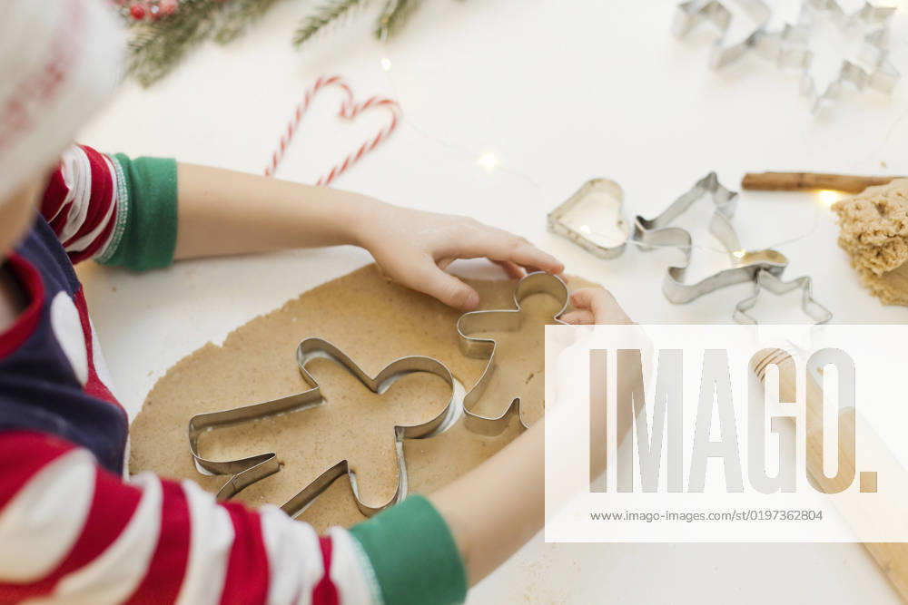 Hands of boy using cookie cutter on gingerbread dough in kitchen model released, Symbolfoto property released, ONAF00301