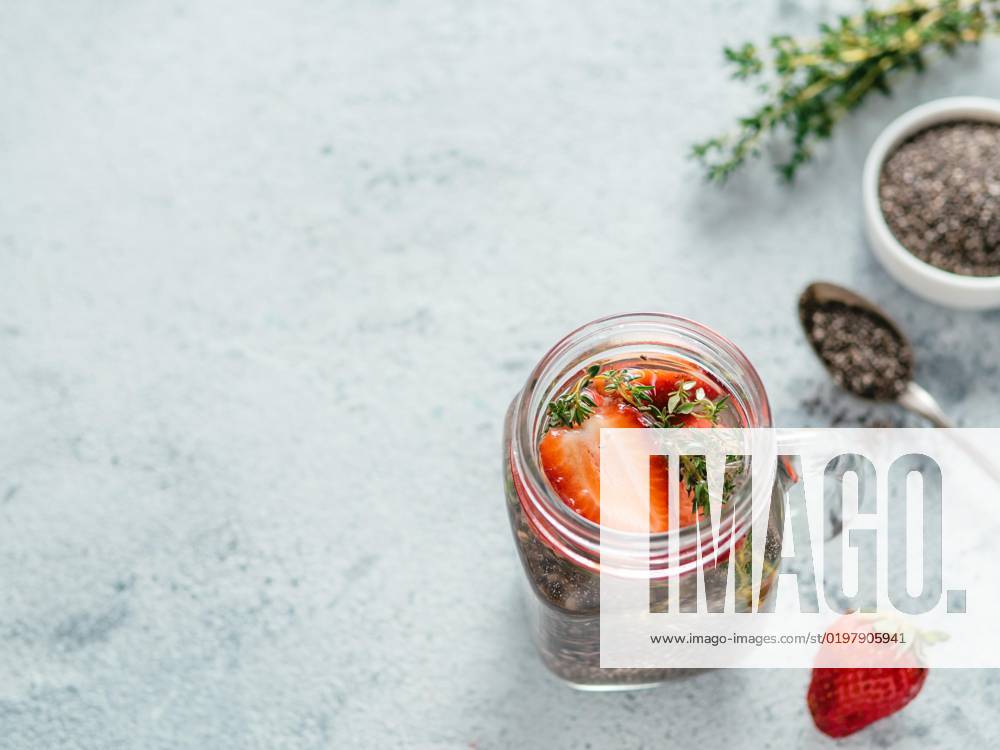 Strawberry and thyme chia water in mason jar, View from above chia water in mason jar with strawberry and thyme on gray cement background. Chia infused detox water with berries. Copy space for text. Healthy eating, drinks, diet, detox concept, 09.11.2019,