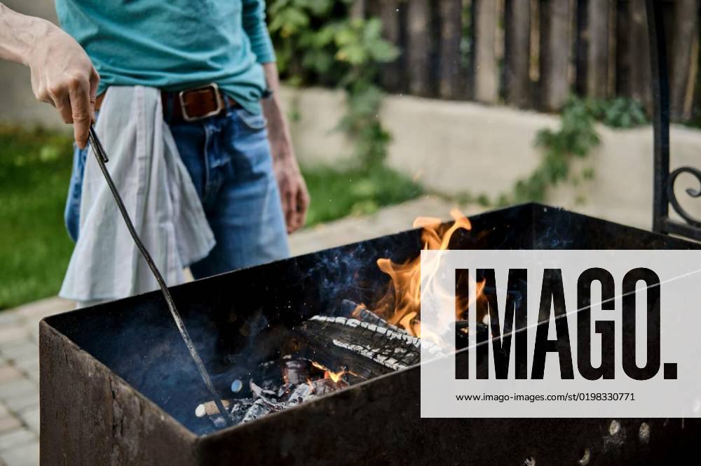 Unrecognisable man stirs the coals in the grill, Unrecognizable man stirs the coals in the grill, Unrecognizable man stirs the coals in the grill model released, Symbolfoto , 06.11.2022,