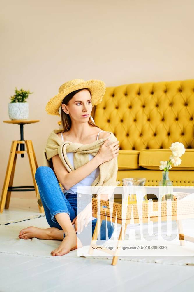 IMAGO Creative, Gesellschaft, Leisure Sickness Barefoot girl in jeans, shirt and straw hat sitting on the floor near side table, Barefoot girl in jeans, shirt and straw hat sitting on the floor near side table with fresh drink, Barefoot girl in jeans, shirt and straw hat sitting on the floor near side table with fresh drink model released, Symbolfoto , 05.12.2022,