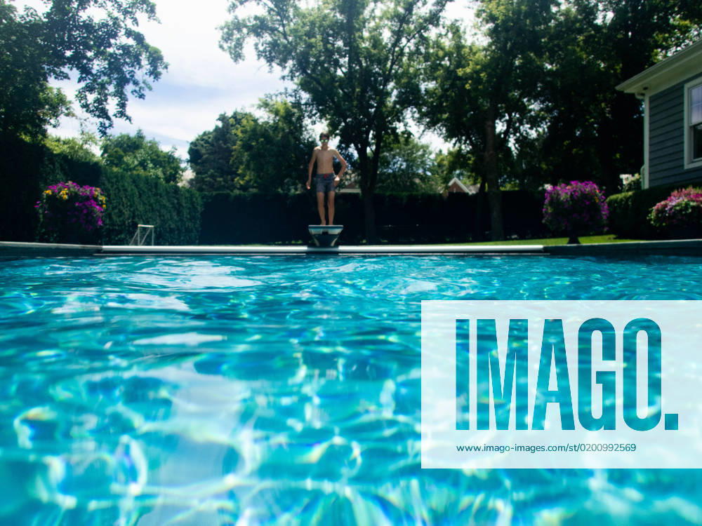 Boy jumps off diving board into backyard pool in summer sunshine Gurnee, Illinois, United States CR_WVNP230125E-1091177-01 ,model released, Symbolfoto
