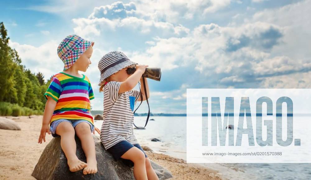 Two children sitting on the stone on the seacoast in summer., Two children sitting on the stone on the seacoast in summer. Concept of the family vacation and tourism., Two children sitting on the stone on the seacoast in summer. Concept of the family vacation and tourism. model released, Symbolfoto , 19.01.2023,