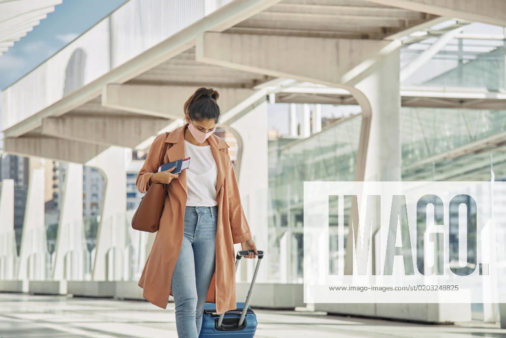 IMAGO Creative, Gesellschaft, Leisure Sickness woman with medical mask walking with her luggage airport during pandemic woman with medical mask walking with her luggage airport during pandemic