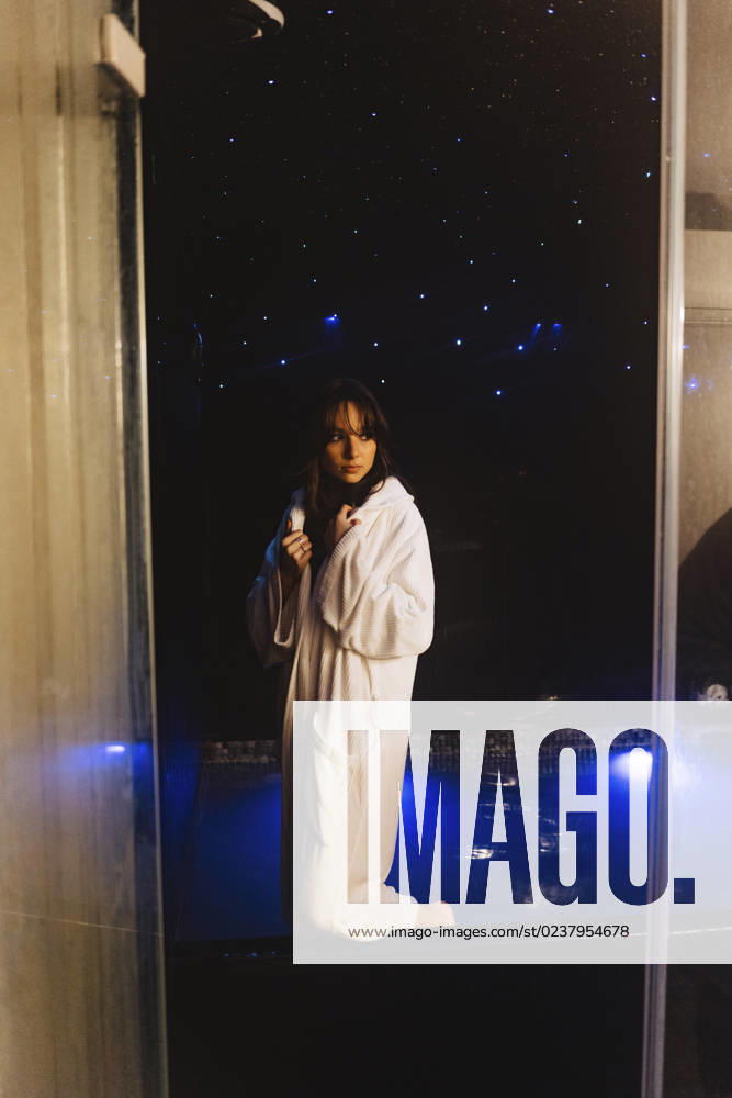 Thoughtful woman wearing bathrobe standing in swimming pool model released, Symbolfoto property released, JJF00117