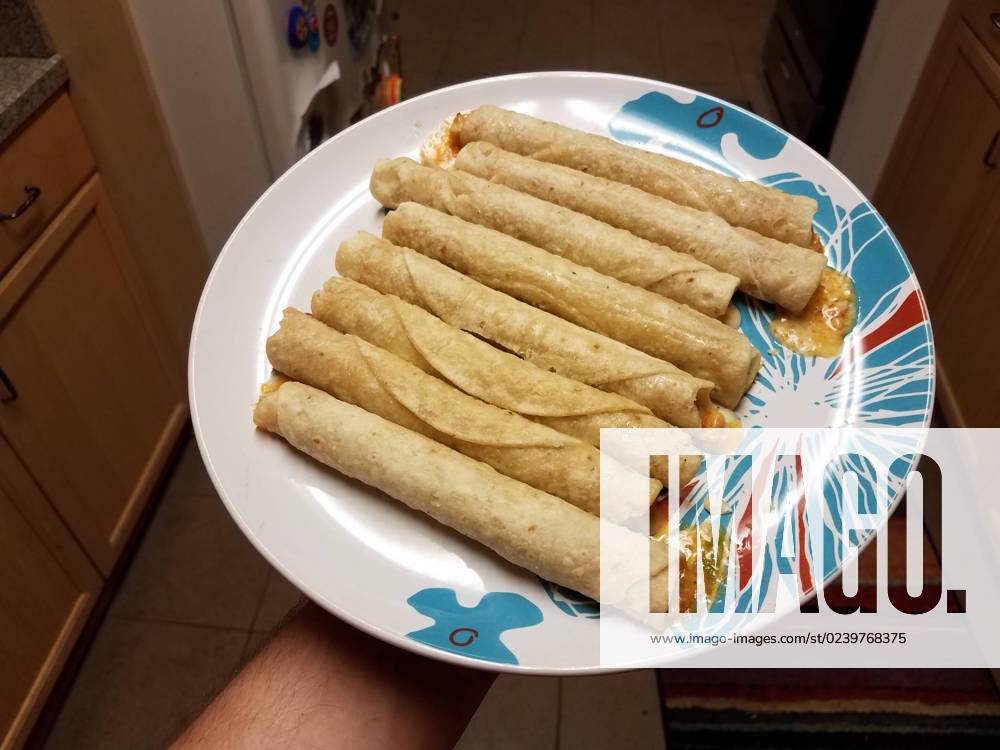 IMAGO Creative, Food, Taquitos hand holding hot taquitos on plate in kitchen , 28044184.jpg, taquitos, texmex, food, hot, cheese, cheesy, plate, hand, holding, lunch, dinner, snack, junk food, kitchen, mexican, melted