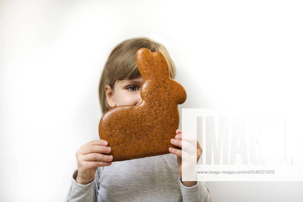 Girl with gingerbread Easter bunny covering face against white background model released, Symbolfoto, MOMF01009