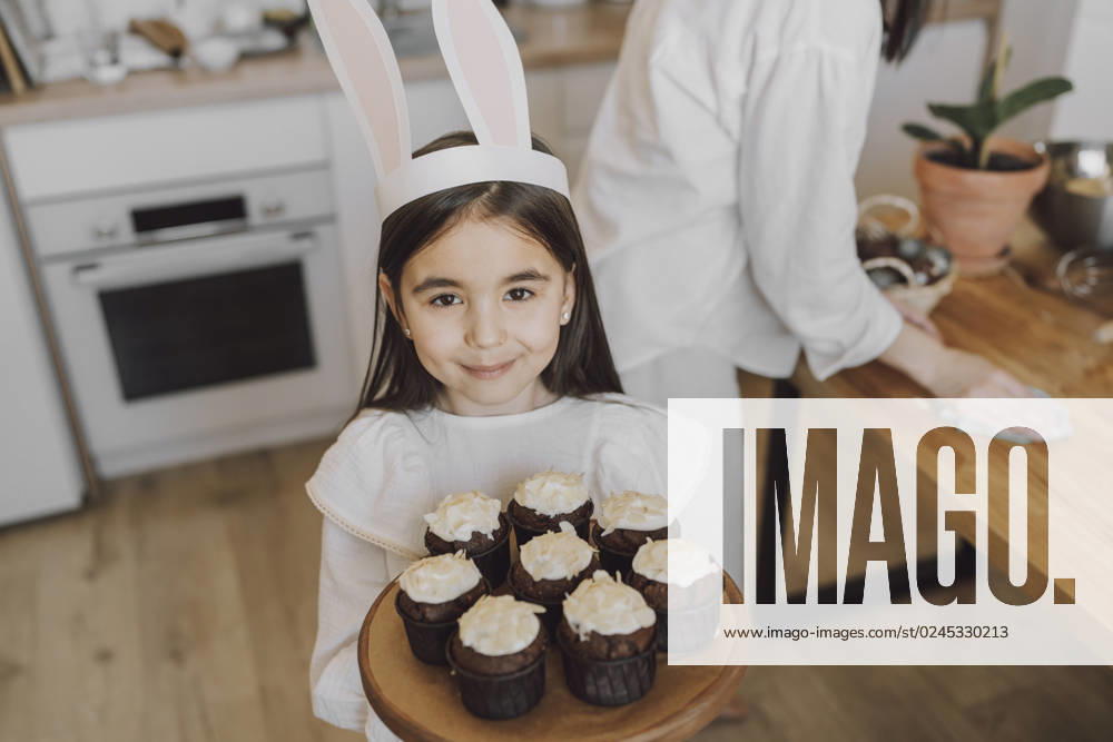 Smiling girl holding cupcakes on Easter day at home model released, Symbolfoto property released, VBUF00303