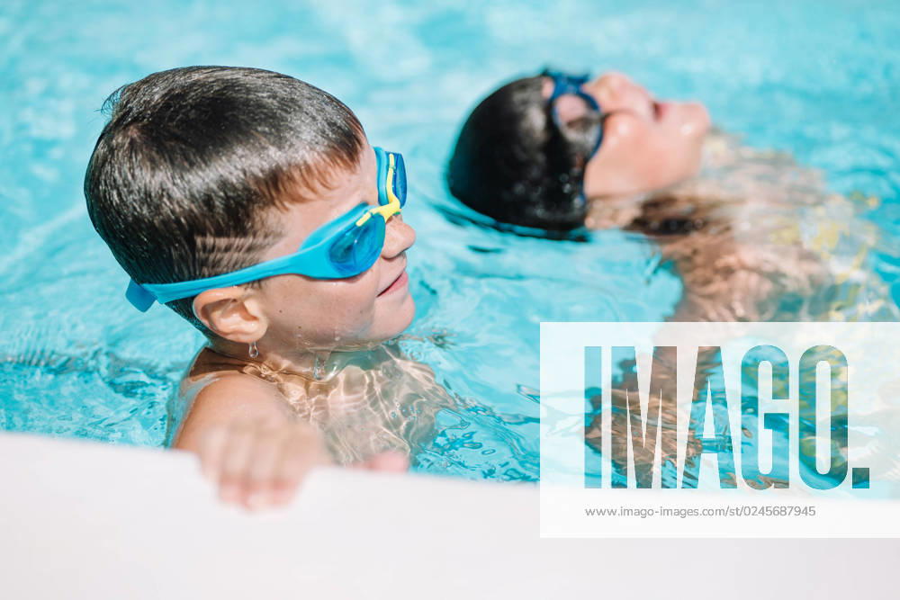 IMAGO Creative, Jahreszeit Sommer, Sommerferien Cute kids swimming in pool Little boys wearing diving glasses and swimming together in clean water of pool while enjoying time during holidays HodeiUnzueta_ID13469_409918_014