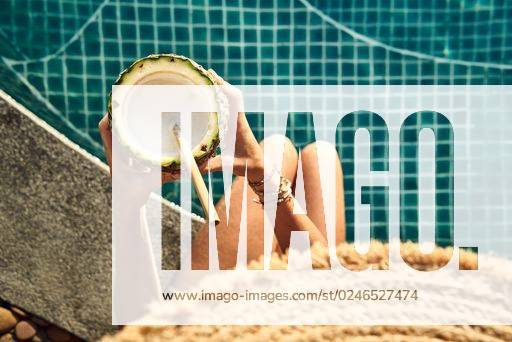 A top view of a woman having a pineapple drink at the pool *** einer Spitze Ansicht des einer Frau habend einer Ananas trinken im der Bassin 3670018