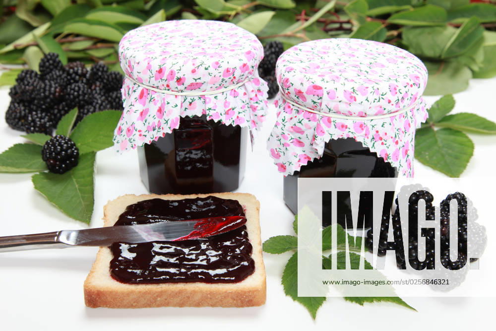 Two glasses of homemade blackberry jam with fresh fruits, toast and leaves