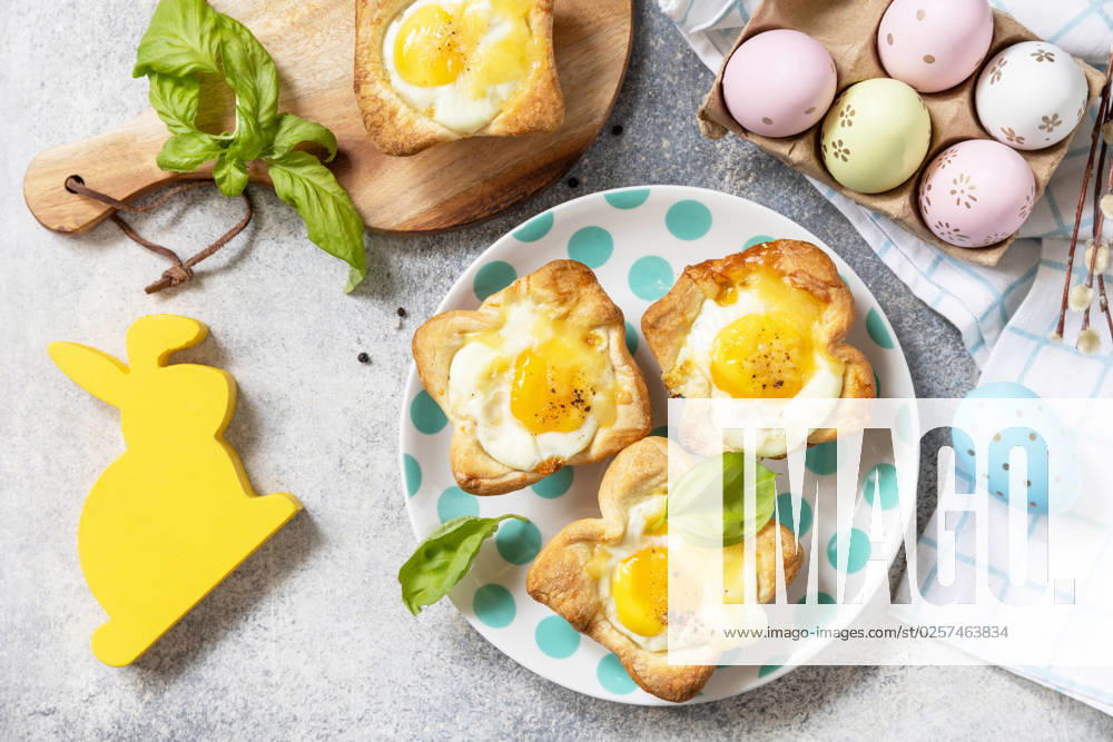 Easter breakfast idea. Scrambled eggs in puff pastry with cheese and bacon on a stone background. View from above. Easter breakfast idea. Scrambled eggs in puff pastry with cheese and bacon on a stone background. View from above.