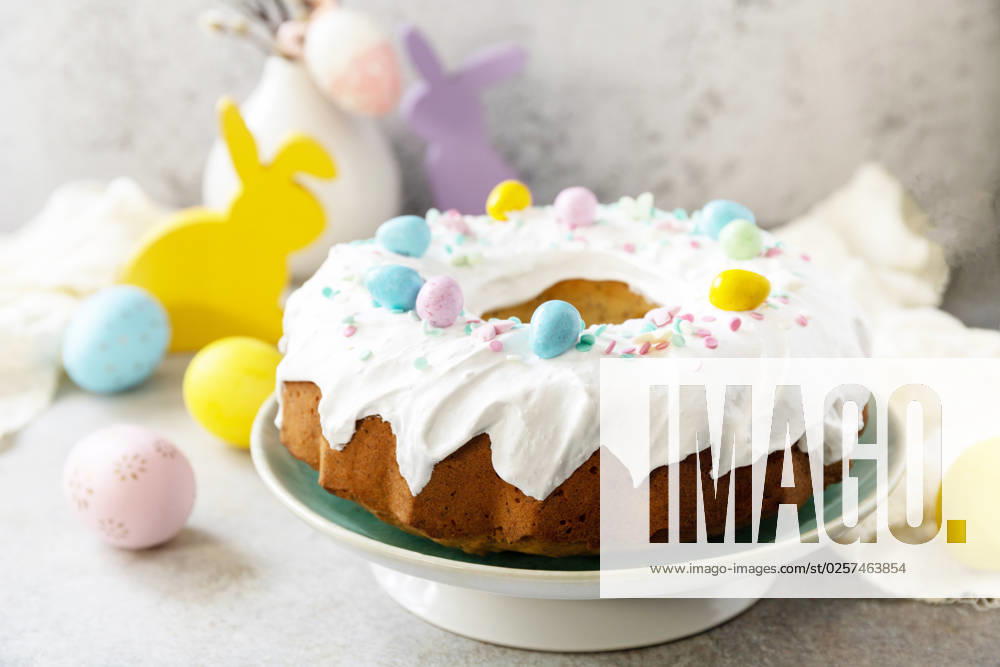 Glazed easter lemon cake decorated with confectionery and mini chocolate eggs candy on gray stone background. Happy Easter holidays, tasty dessert. Copy space. Glazed easter lemon cake decorated with confectionery and mini chocolate eggs candy on gray stone background. Happy Easter holidays, tasty dessert. Copy space.