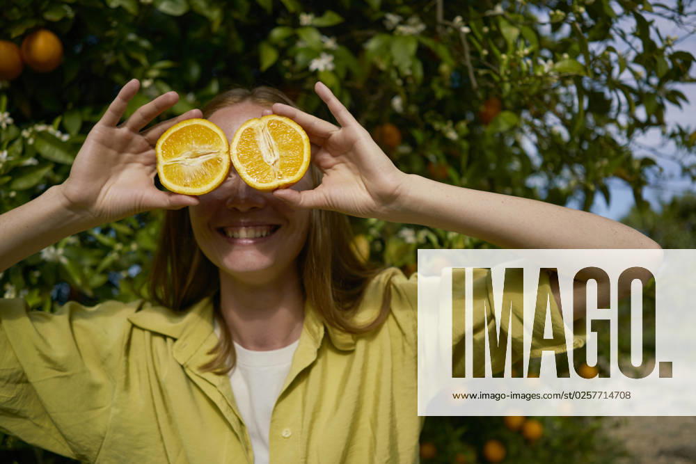 Woman covering eyes with orange slices at orchard model released, Symbolfoto property released, ANNF00237