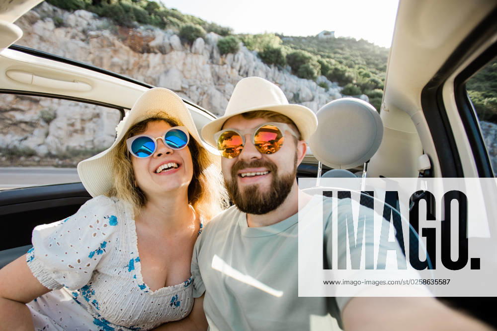 Romantic couple making selfie on smartphone camera in rental cabrio car on ocean or sea beach enjoying summer vacation together and taking picture on cellular resting near sea on weekends Romantic couple making selfie on smartphone camera in rental cabrio car on ocean or sea beach, enjoying summer vacation together and taking picture cellular resting near sea on weekends ,model released, Symbolfoto