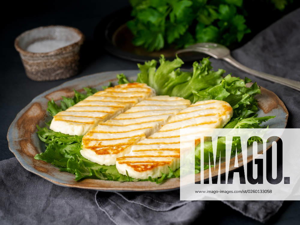 Grilled Halloumi, fried cheese with lettuce salad. Balanced diet on dark background, side view Grilled Halloumi, fried cheese with lettuce salad. Balanced diet on dark background, side view
