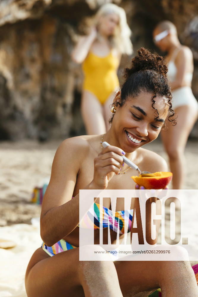 Young woman in bikini enjoying mango at beach model released, Symbolfoto, EBSF03360