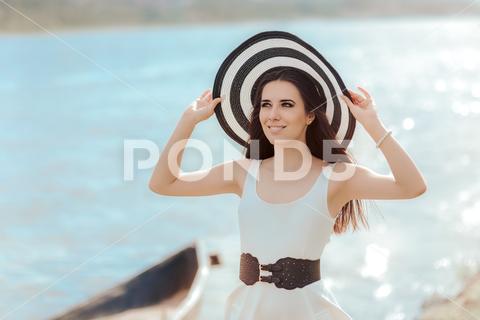 Beautiful girl in a white dress on the seashore near a boat Woman, girl, young, beautiful, straw, hat, dress, white, black, retro, vintage, elegant, style, stylish, stripes, sea, seashore, shore, boat, water, summertime, season, portrait, belt, big, oversized, outfit, lovely, fashion, sun, beach, sunlight, vitamin D, heliotherapy, tourist, tourism, vacation, holiday, littoral, pretty, pearls, bracelet, smile, happy, perfect, weather