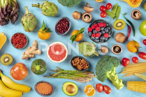 Vegan food. Healthy diet concept. Fruits, vegetables, pasta, nuts, legumes, mushrooms, shot from above on a blue background. A flat lay composition vegan, vegetarian, food, healthy, diet, background, fruit, vegetable, pasta, mushrooms, legumes, pulses, overhead, above, view, top, shot, flat, lay, flat lay, flatlay, nuts, table, cooking, kitchen, raw, fresh, nutrition, ingredient, concept, veg, produce, supermarket, organic, vitamin, protein, carbohydrate, fiber, wholesome, natural, superfood, grapefruit, artichoke, broccoli, various, variety, assortment, many, different, blue