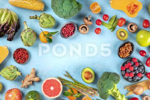 Vegan food. Healthy diet concept. Fruits, vegetables, pasta, nuts, legumes, mushrooms, shot from above on a blue background, forming a frame with a place for text. A flat lay composition vegan, vegetarian, food, healthy, diet, background, fruit, vegetable, pasta, mushrooms, legumes, pulses, overhead, above, view, top, shot, flat, lay, flat lay, flatlay, nuts, table, kitchen, raw, fresh, nutrition, ingredient, veg, produce, organic, vitamin, fiber, wholesome, grapefruit, artichoke, broccoli, variety, many, frame, copy, space, copyspace, copy space, place, text, ginger, design, template, menu