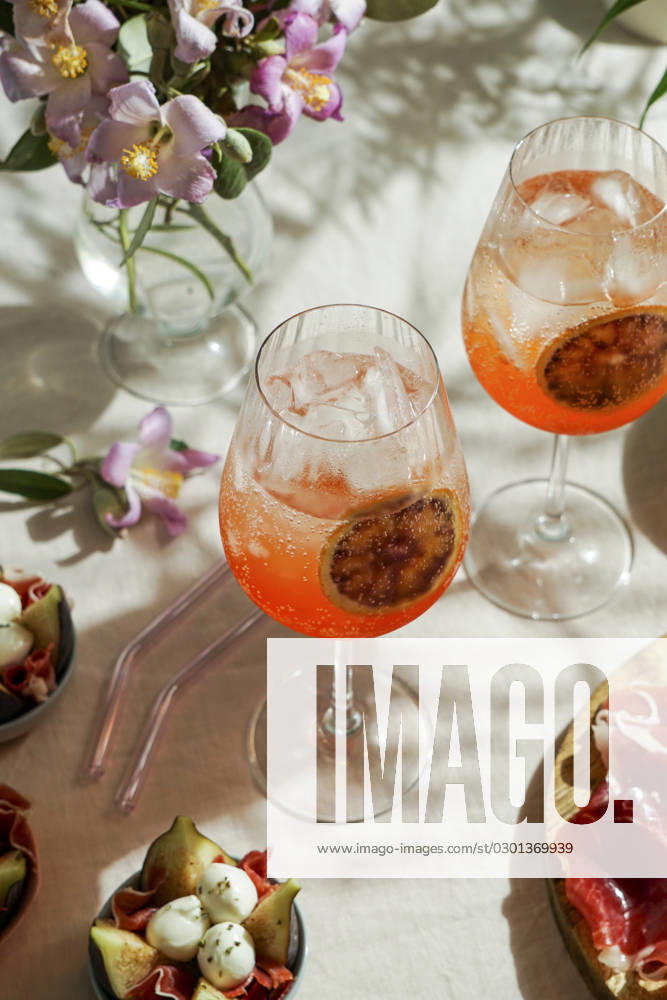 Aperol spritz cocktail, on a pale pink linen tablecloth, shadows, sunlight, summer drink in glass aperol spritz cocktail, on a pale pink linen tablecloth, shadows, sunlight, summer drink in glass