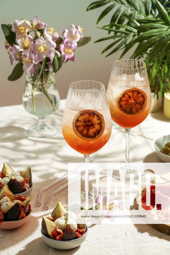 Aperol spritz cocktail, on a pale pink linen tablecloth, shadows, sunlight, summer drink in glass aperol spritz cocktail, on a pale pink linen tablecloth, shadows, sunlight, summer drink in glass