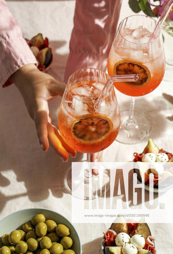 Aperol spritz cocktail, on a pale pink linen tablecloth, shadows, sunlight, summer drink in glass aperol spritz cocktail, on a pale pink linen tablecloth, shadows, sunlight, summer drink in glass