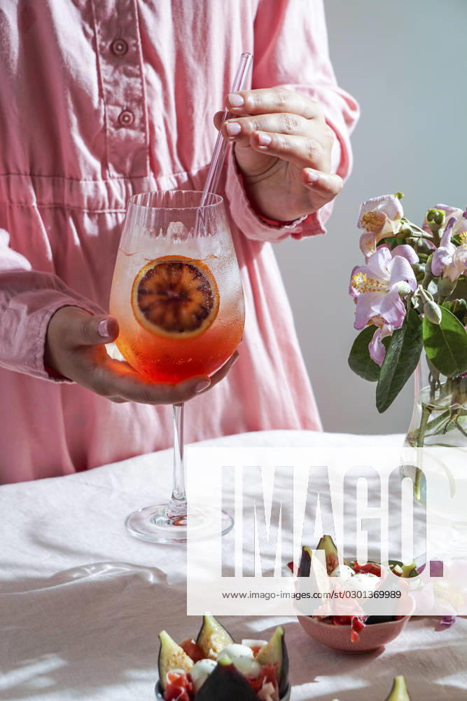 Aperol spritz cocktail, on a pale pink linen tablecloth, shadows, sunlight, summer drink in glass aperol spritz cocktail, on a pale pink linen tablecloth, shadows, sunlight, summer drink in glass