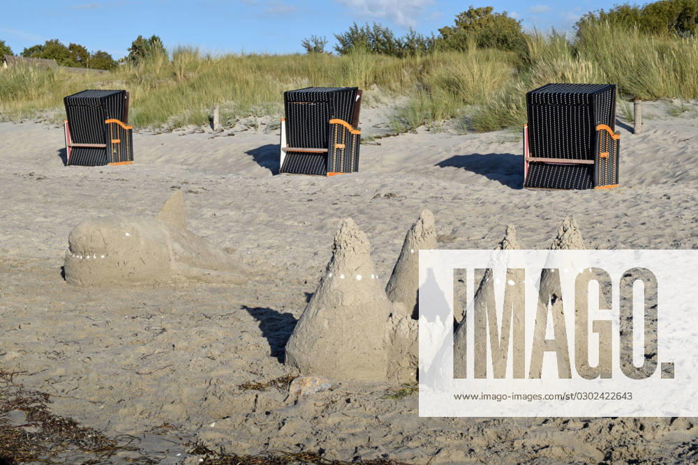 island Poel beach art Germany Mecklenburg Vorpommern island Poel Baltic Sea coast on the beach sand beach art left a fish whale formed from sand the eyes and teeth are made of shells right a sand castle behind it three brown beach chairs