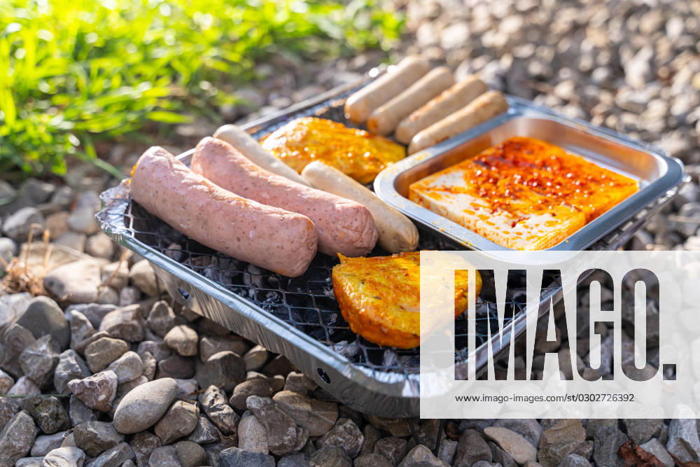 Bavaria, Germany - 2 September 2023: Vegetarian Grilling, Bratwurst Vegan and Vegetarian on a disposable grill on pebbles next to a meadow. Meat and sausage substitutes