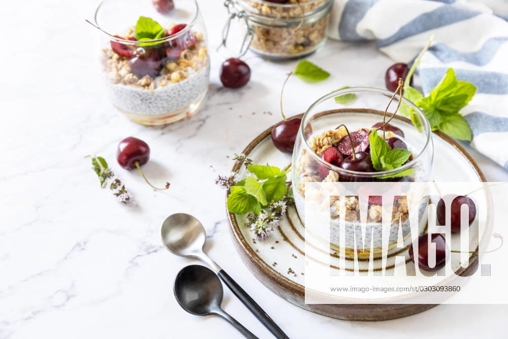 Healthy menu concept. Home made granola breakfast. Glass of parfait made of granola, berries cherry, yogurt with chia seeds on rustic table. Copy space. Healthy menu concept. Home made granola breakfast. Glass of parfait made of granola, berries cherry, yogurt with chia seeds on rustic table. Copy space.