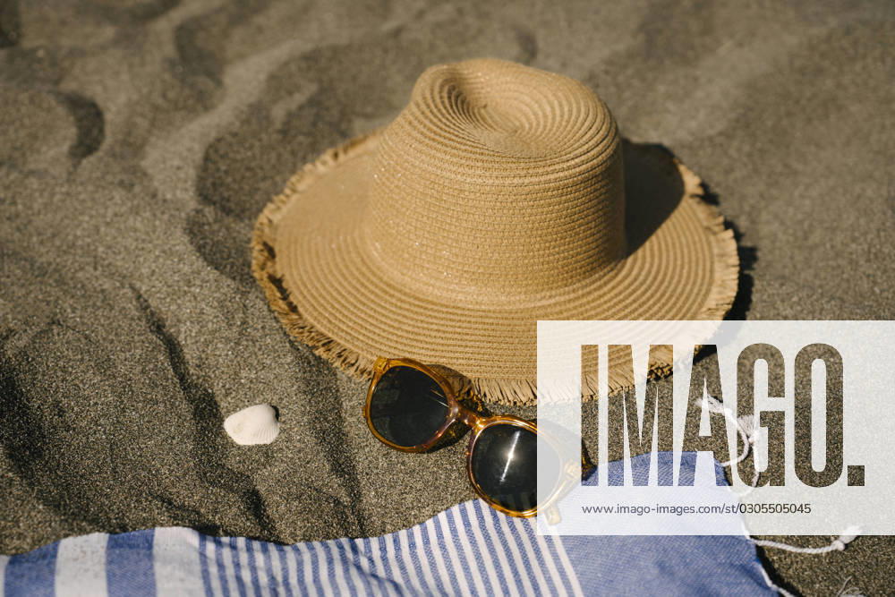 Sun hat next to sunglasses on sand at beach, YBF00201